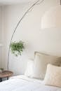 这间明亮的极简主义卧室配有舒适的枕头和悬挂的室内植物，是放松身心的理想选择