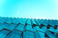 在鲜艳的蓝天下，现代玻璃建筑立面的低角度视图呈现出动态的反射