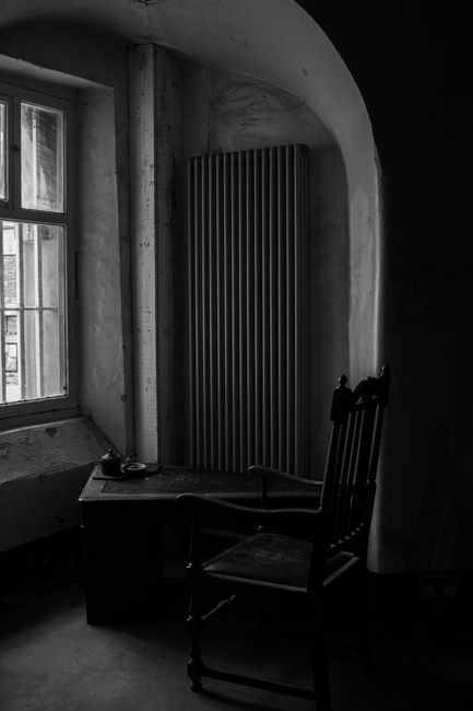 Monochrome image of a vintage room with an antique chair and natural light streaming in.