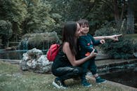 在公园的池塘边，母亲和孩子共享着大自然与团聚的快乐时光