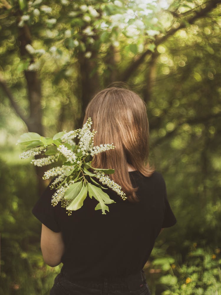 Back View Photo Of Woman In Black T-shirt Holding Plant