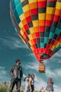 一个色彩缤纷的热气球翱翔在享受户外冒险刺激的人群上空