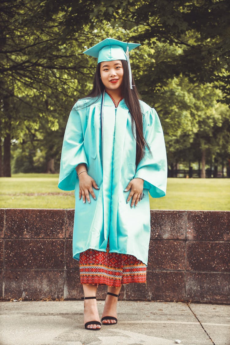 Photo Of Standing Woman In Blue Academic Regalia Smiling