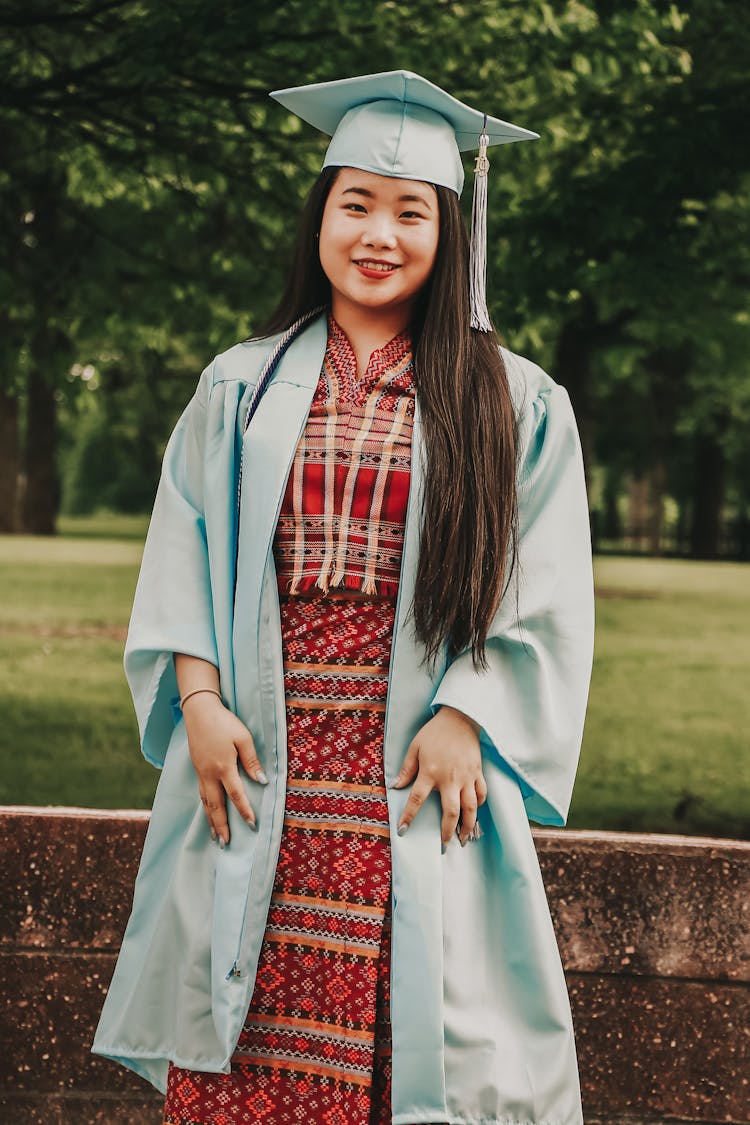 Photo Of Standing Woman In Blue Academic Regalia Smiling