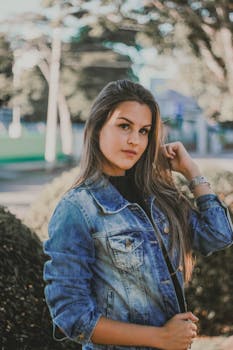 一位时尚的女人在户外穿着牛仔夹克，在自然光下摆姿势