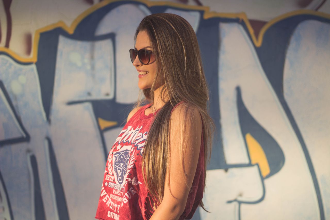 casual fashion portrait of a smiling woman posing by a vibrant graffit