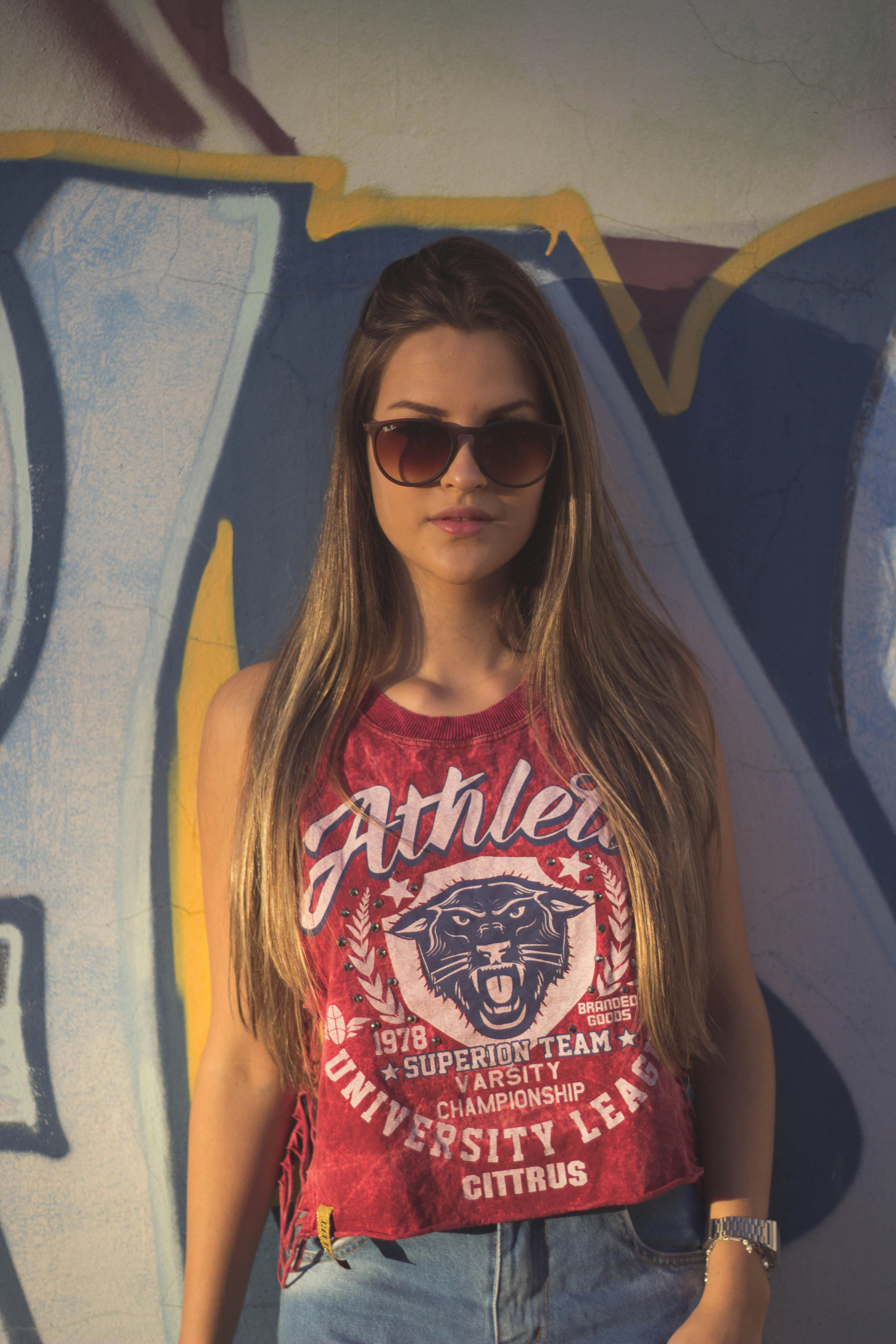 一位戴着墨镜的时尚女士，在充满活力的涂鸦墙前摆姿势