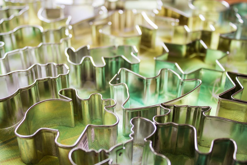 Close-up of diverse metal cookie cutters in abstract shapes on a colorful surface.