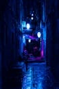 充满活力的蓝色灯光照亮了城市小巷的夜色，潮湿的地面映出光影