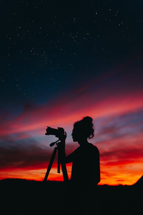 Silhouette of Woman Photographer Using Camera at Night