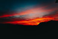 巴西圣保罗日落时分，迷人的山脉轮廓映衬着充满活力的红橙色天空