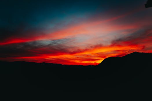 巴西圣保罗日落时分，迷人的山脉轮廓映衬着充满活力的红橙色天空