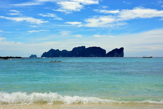 Relaxing beach scene in Ao Nang, Krabi, Thailand with clear blue waters and distant islands.