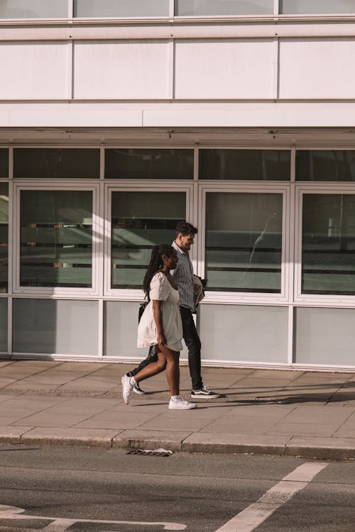 A couple walking down the street in front of a building