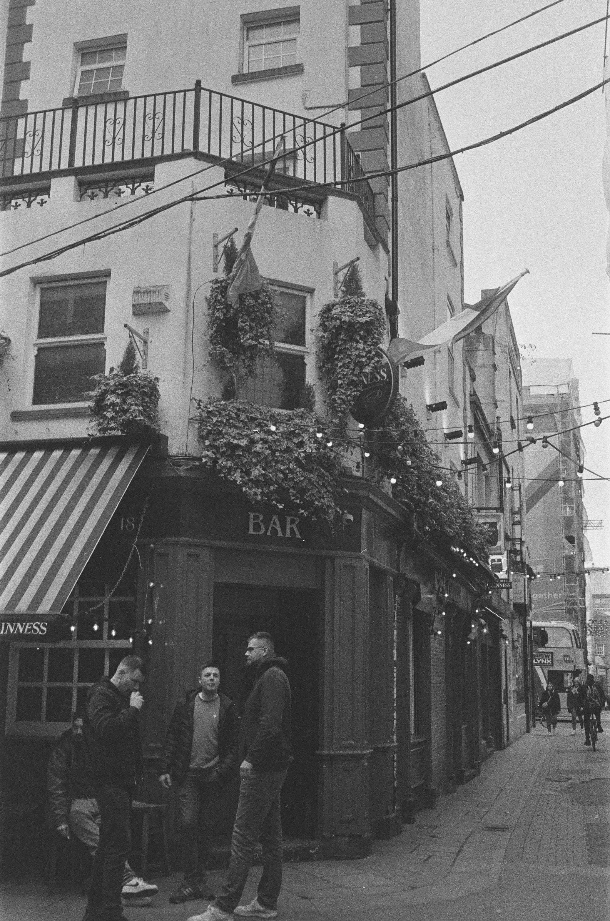 black and white photo of a group of men standing in front of a bar