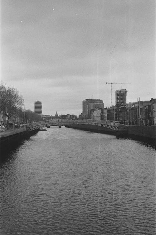 A black and white photo of a river with buildings in the background