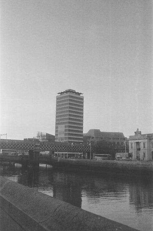A black and white photo of a building next to a river
