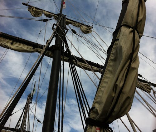 曇り空の下で船に巻き上げられた帆のローアングル写真