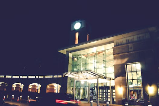 城市晚报：钟楼在现代玻璃建筑群中夜间亮灯