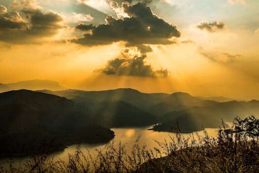 Breathtaking view of sunset rays over mountains and lake in Kerala, India.