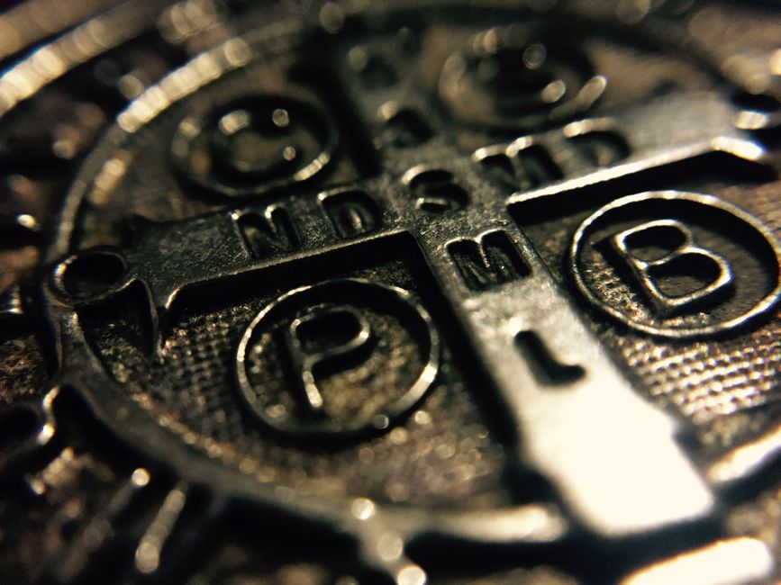 Macro shot of a metallic Saint Benedict medal with intricate religious inscriptions.