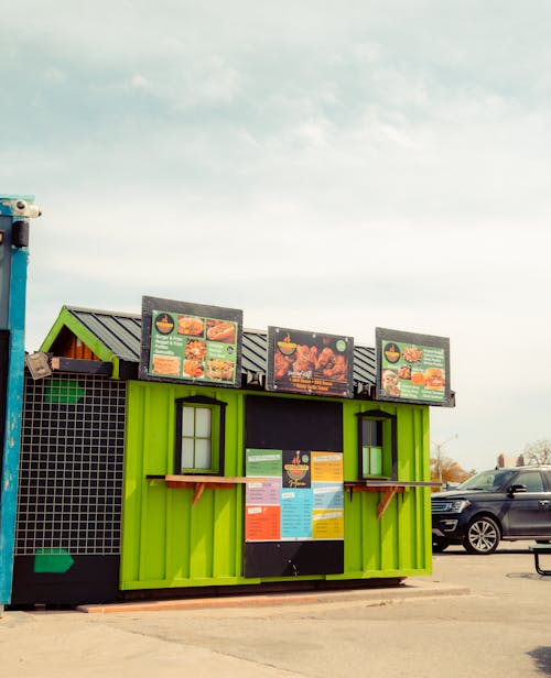 A small green and black food truck parked in a parking lot