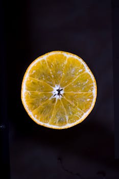 在黑色背景下，明亮的新鲜柑橘片凸显出其充满活力的纹理和颜色