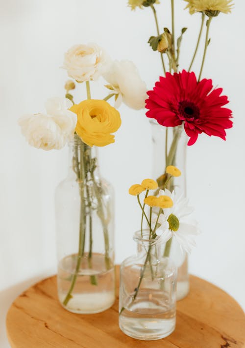 Three vases with flowers in them on a wooden table
