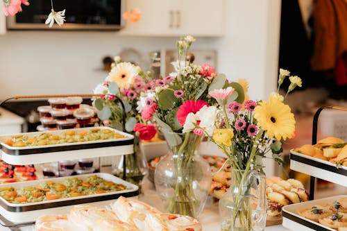 A buffet table with food and flowers on it