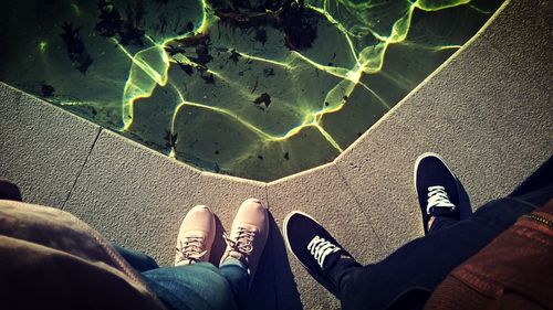 Free A pair of casual sneakers next to a pool with sunlit water reflections. Stock Photo