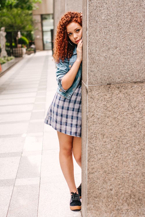 Free Photo of Woman in Blue Denim Jacket and Mini Dress Leaning on Concrete Pillar Stock Photo