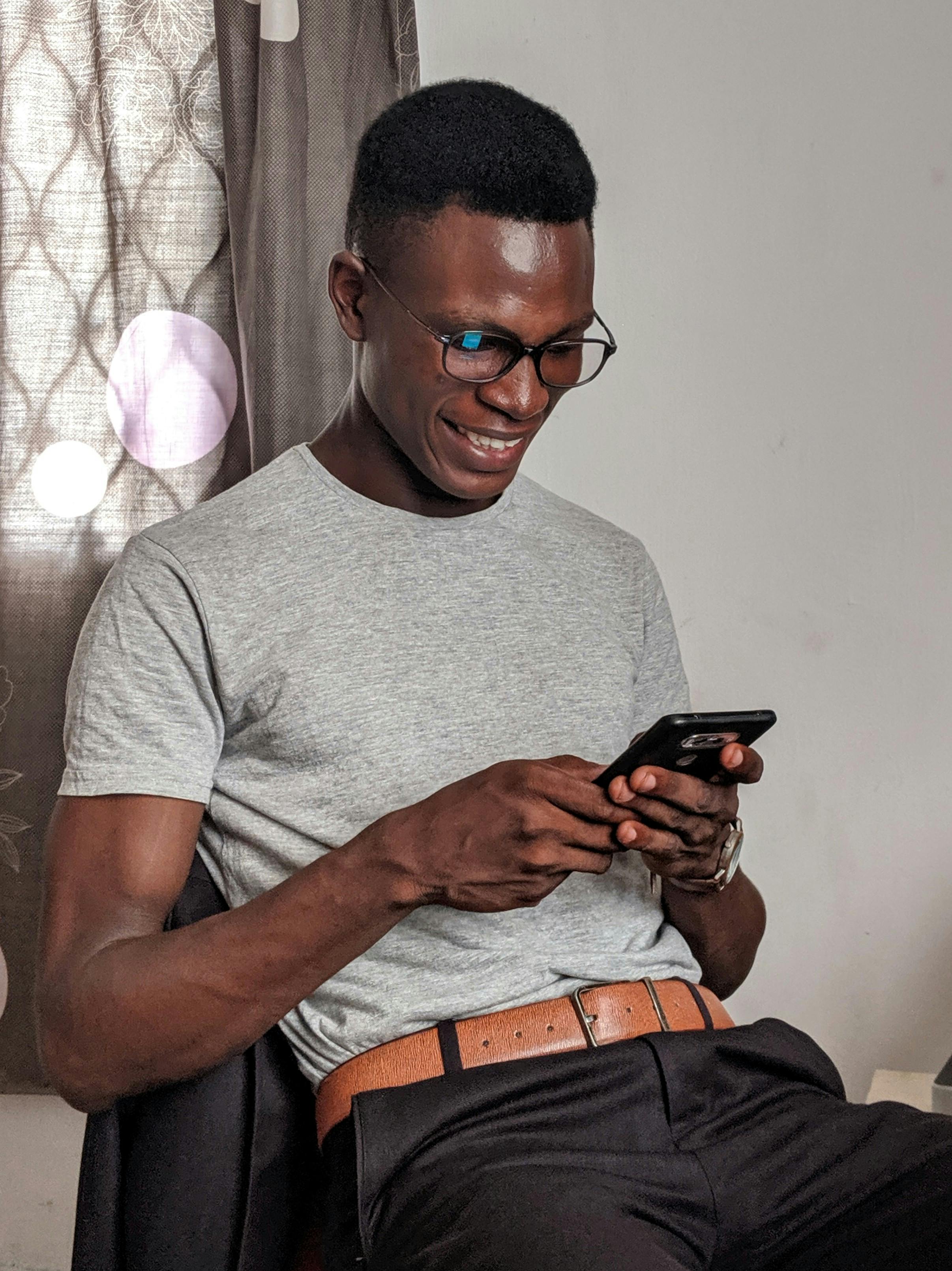 Man Wearing Gray Crew-neck Shirt Holding Black Smartphone