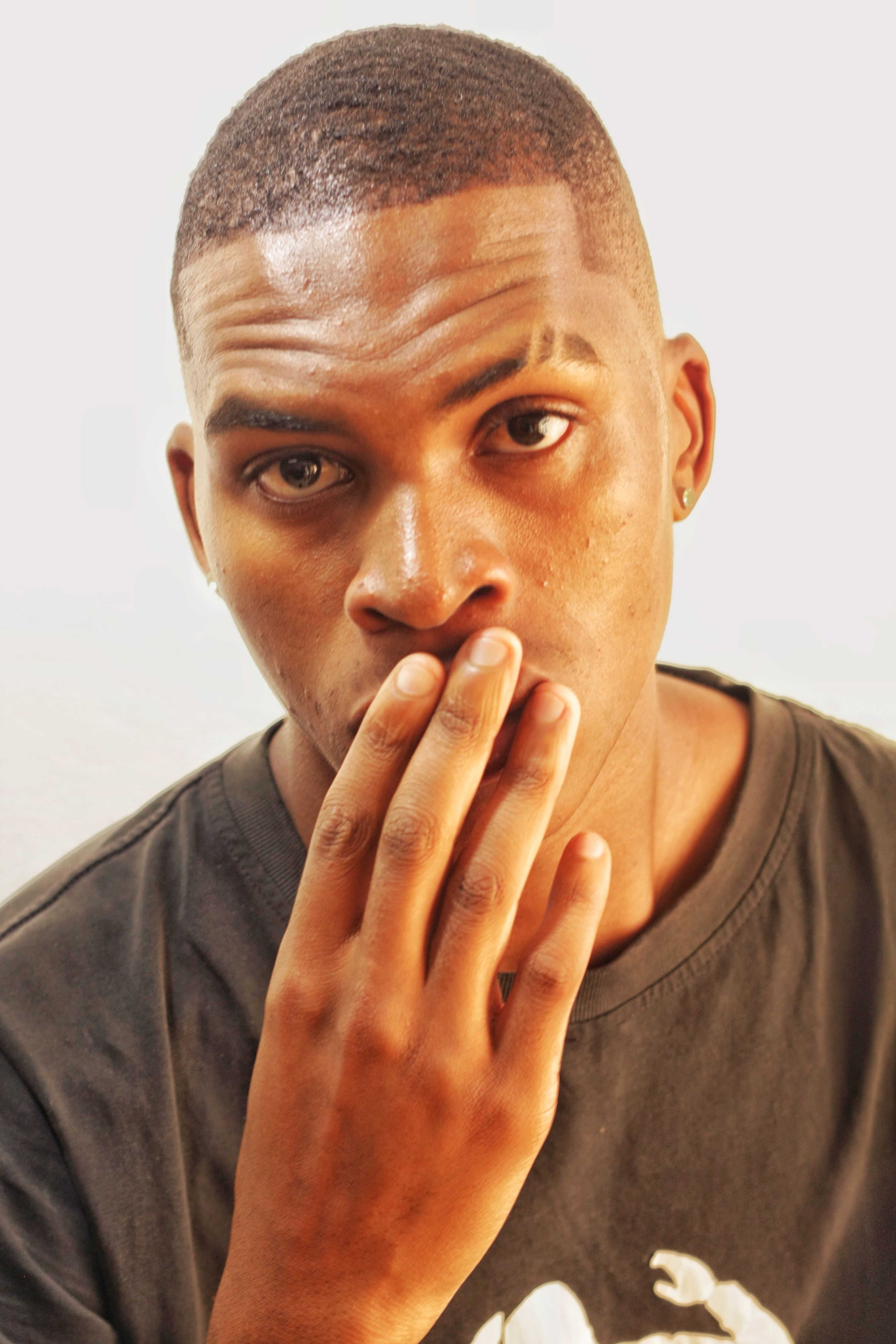 Portrait of a thoughtful young man with hand on mouth on a white background.