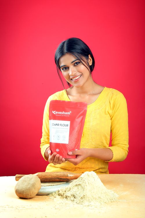 Free A smiling woman holding a packet of jowar flour, set against a vibrant red background in a studio shoot. Stock Photo