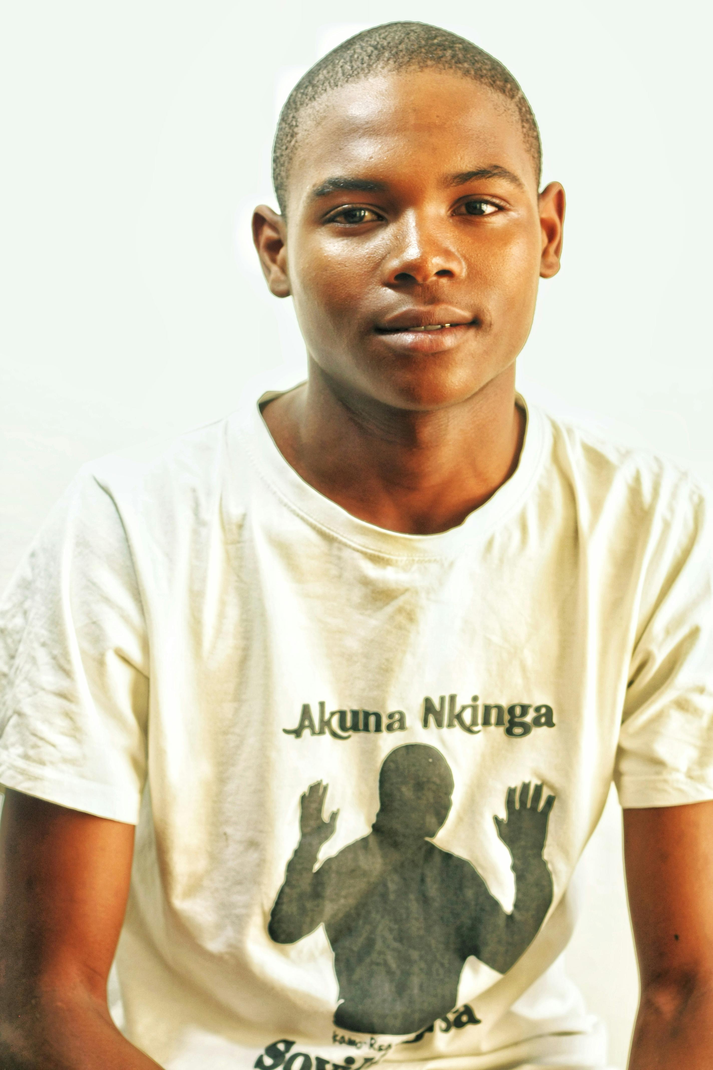 Portrait of a young man wearing a white graphic t-shirt with short hair.
