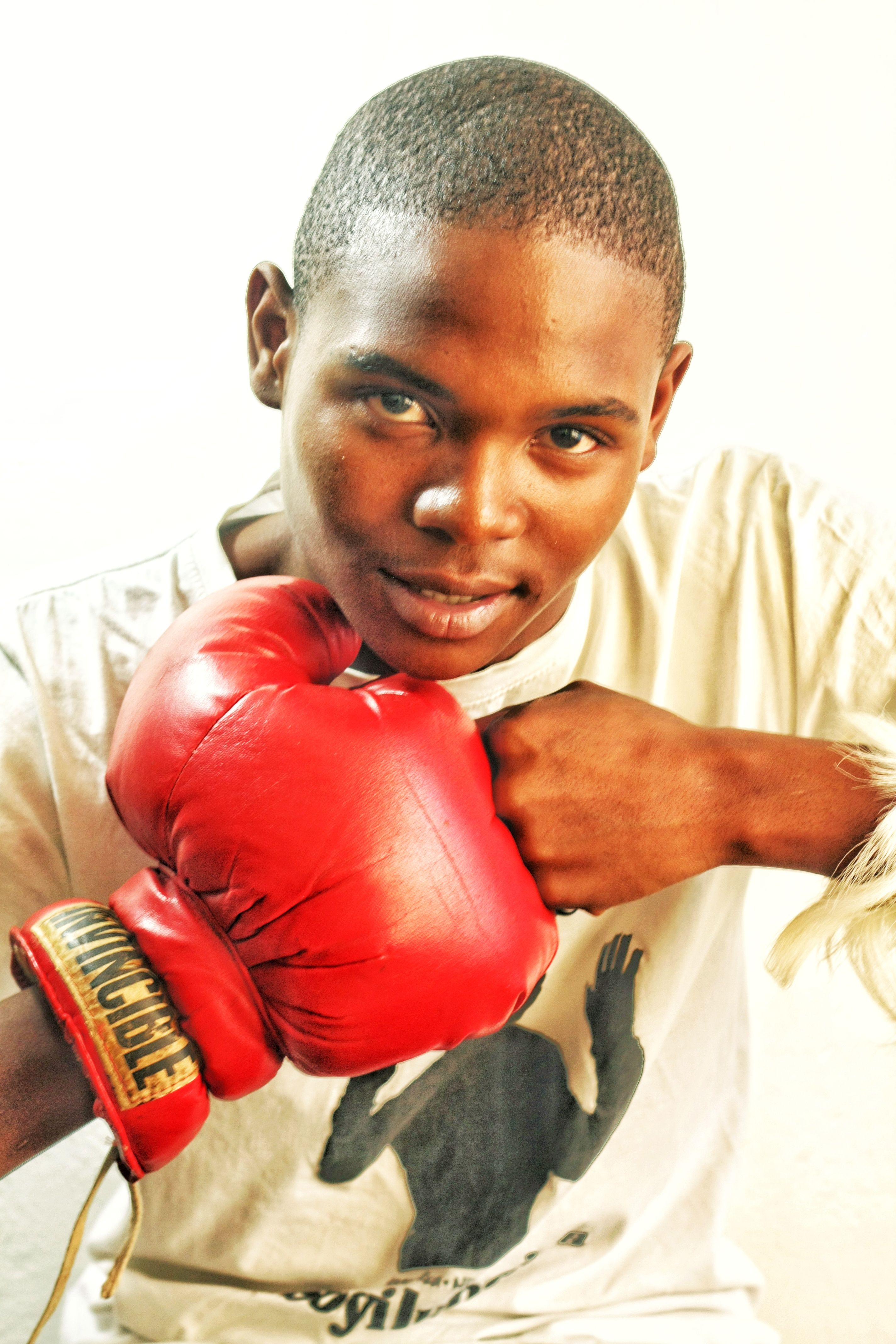 Dynamic portrait of a young boxer posing with red gloves in a studio setting.