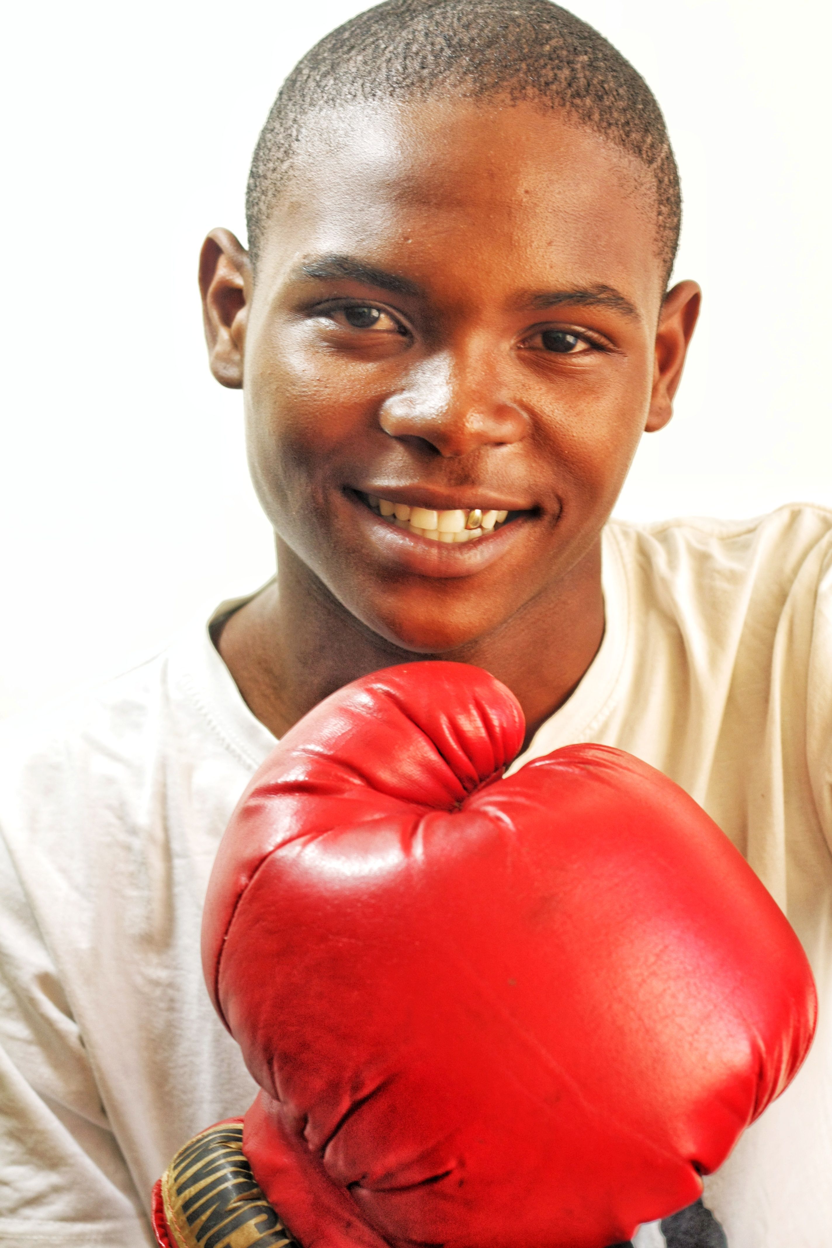 Optimistic young boxer smiling confidently with red boxing gloves in a studio setup.