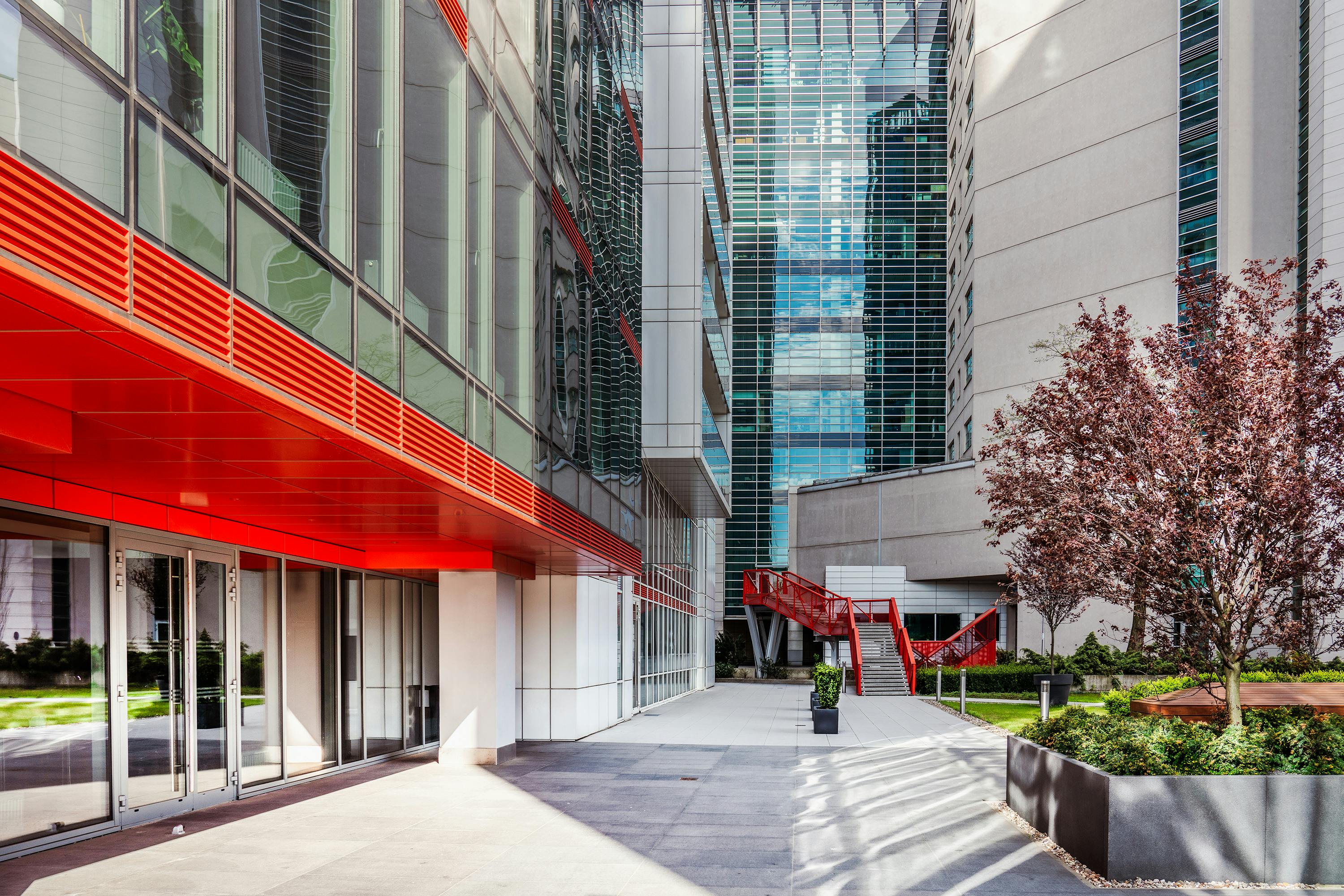 Contemporary office building exterior in Poznań with vibrant red accents and glass facade.