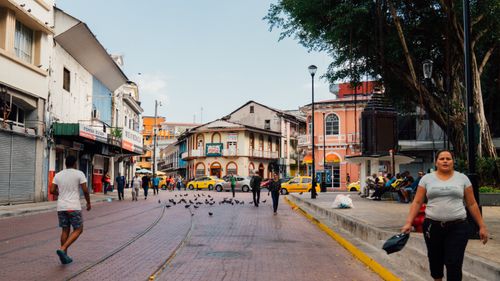 Free Busy urban street with people, pigeons, and taxis, showcasing colorful architecture. Stock Photo
