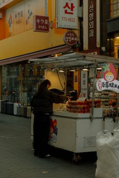 Person buying street food in an urban Asian market setting with colorful signage.