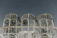 现代温室与钢和玻璃结构映衬着晴朗的天空，呈现出标志性的建筑设计