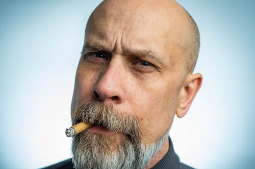 Крупным планом фотография бородатого мужчины с сигаретой во рту