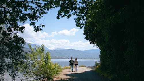 Two people walking on a path near a lake