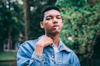 一名穿着牛仔布、嘴里叼着雏菊的年轻人在户外拍摄特写肖像