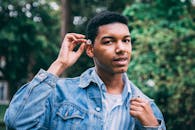 一个穿着牛仔夹克的年轻人在户外自然环境中手持雏菊的休闲肖像