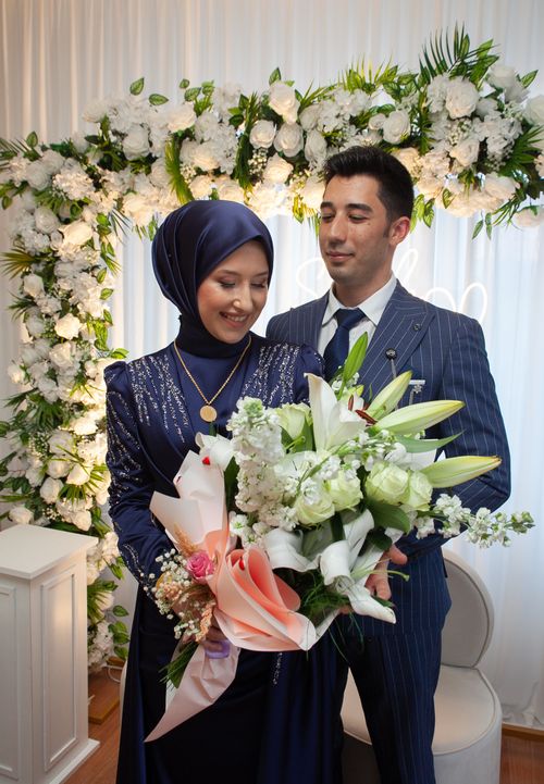 Free Bride and groom in elegant attire with a beautiful floral bouquet, capturing a joyful wedding moment. Stock Photo