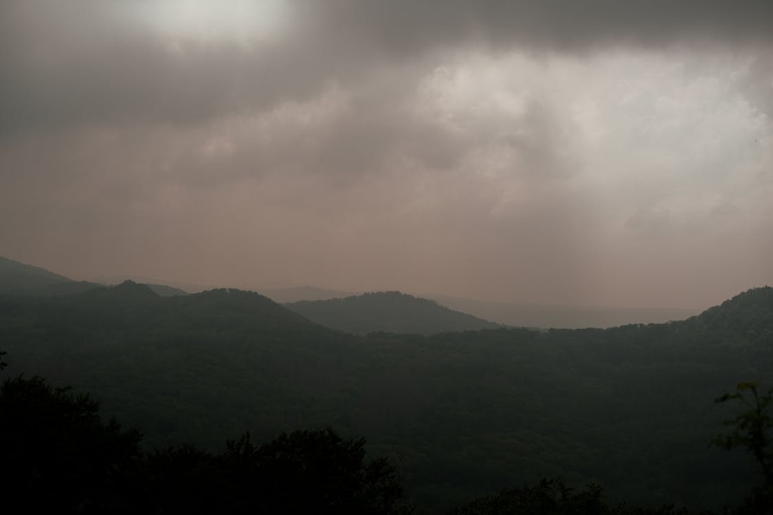 A dark sky with mountains and trees in the distance