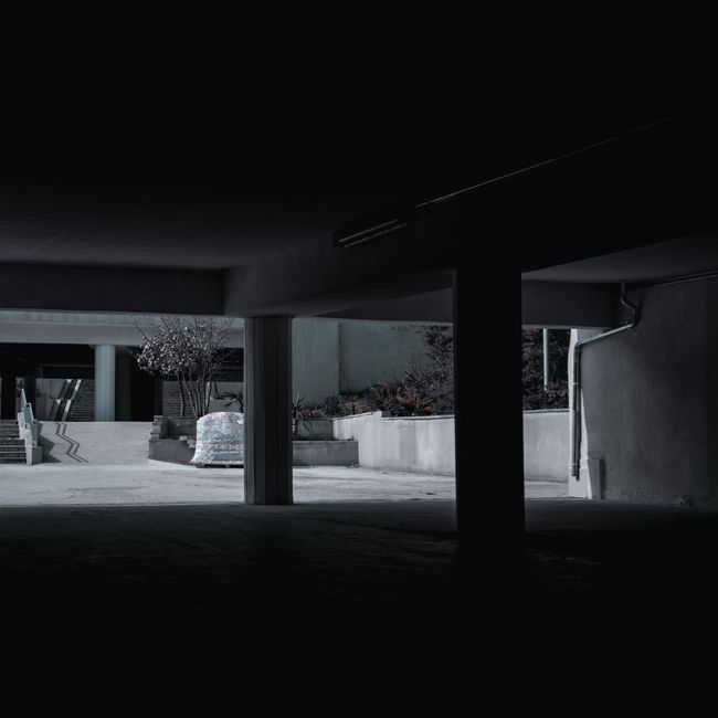 A dark and empty urban garage showcasing modern architecture and concrete structures.