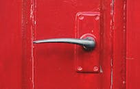 一扇亮红色漆门的特写，门上装有金属把手