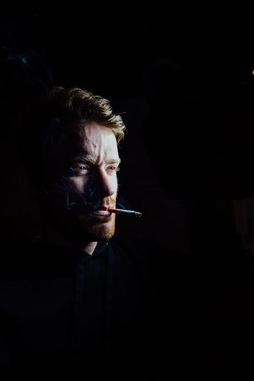 Low Light Photo of Man Smoking Cigarette